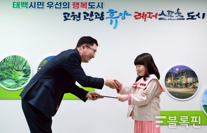 나채범 한화손해보험 대표이사가 태백출신 아역배우 유슬에게 창작동화 '땅요가 알려주는 석탄 이야기'를 전달하고 있다. 사진ㅣ한화손해보험