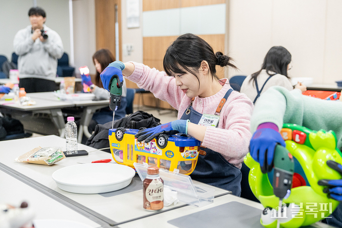 롯데의 밸유 봉사단 단원이 장난감을 수리하는 사회봉사활동을 펼치고 있는 모습 사진|롯데