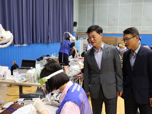 여운철 NH농협생명 부사장(가운데)과 김기동 부장이 치과치료받는 조합원을 살피는 모습. 사진ㅣNH농협생명